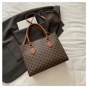 Detailed shot of retro monogram tote bag with gold hardware on grey suit fabric