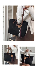 Detail of black suede tote bag with brown leather straps and cute plush bear charm