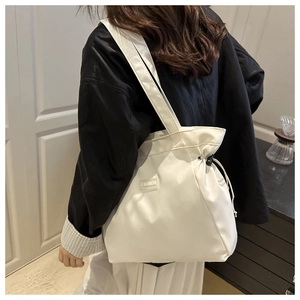 Detail of white nylon tote bag showing black drawstring closure and FASHION woven label