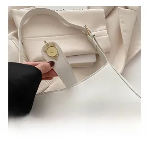 Detail of vintage pale gold magnetic clasp on a minimalist white leather handbag