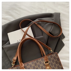Detail shot of vintage brown monogram pattern tote bag with leather straps and gold buckles