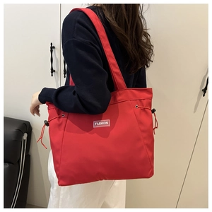 Detail view of red canvas tote bag with drawstring design and FASHION logo label
