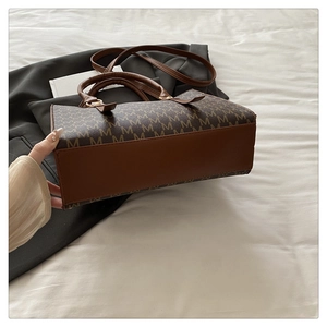 Detail view of large capacity tote bag with dark brown M-letter print and leather straps