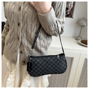 Close-up of black monogram crescent bag with leather brand tag and silver zipper detail