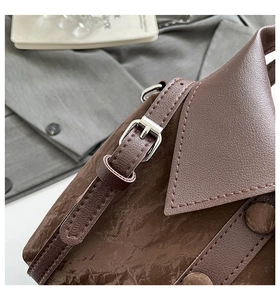 Détail du sac plissé marron avec bandoulière réglable et boucle en métal argenté brillant