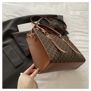 Detail of monogram tote bag featuring M pattern, dual handles, and golden hardware accents
