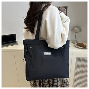 Macro view of large black tote bag with FASHION label and adjustable side drawstring details