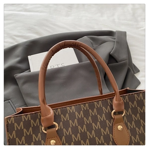Detail of classic tote bag featuring brown monogram M pattern and golden hardware