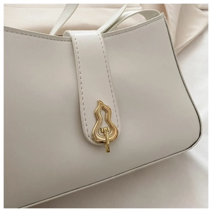 Gros plan d'un sac à bandoulière blanc vintage avec une boucle dorée ondulée unique