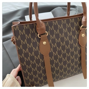 Detailed macro of the vintage monogram tote bag showing golden studs and leather handles