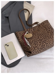 Detailed top view of a leopard print tote bag with plush bear charm and fashion accessories
