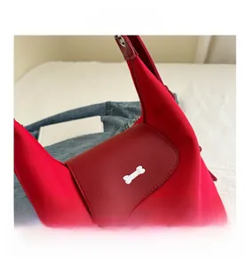 Detailed close-up of red tote bag with fabric texture and bone-shaped metal clasp