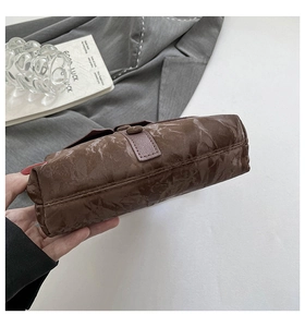 Détail du sac à bandoulière marron foncé avec texture froissée et coutures précises