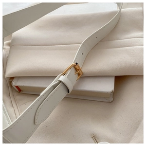 Détail de la bandoulière en cuir blanc avec boucle en métal doré et coutures précises
