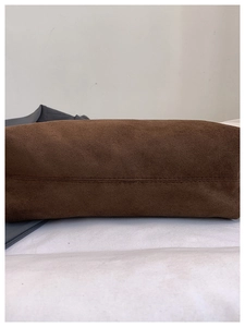 Detail of the stitched bottom on a dark brown suede tote bag with matte leather texture