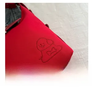 Detail of red canvas tote bag featuring high-quality cartoon dog embroidery and texture