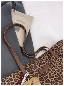 Detailed texture of leopard print tote bag with leather strap and plush bear charm