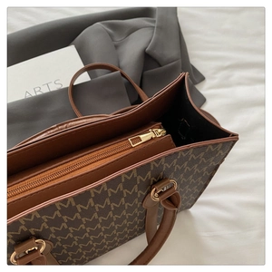 Close-up of brown monogram tote bag showing secure gold zipper and interior compartment