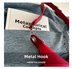 Detail of metal hook and leather strap on a stylish red tote bag over blue denim