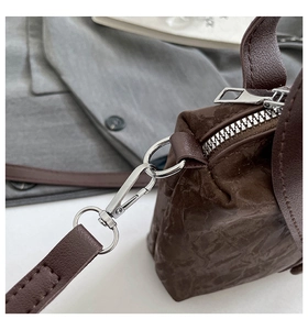 Détail de la fermeture éclair argentée et de la texture cuir marron de ce sac bandoulière chic