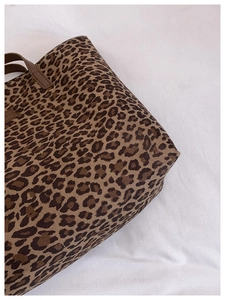 Close-up of leopard print canvas tote bag showing material texture and brown leather handles