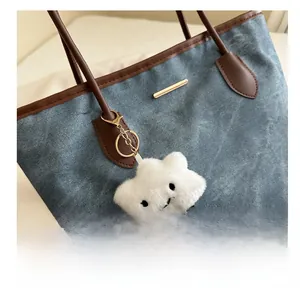 Detail of white plush cloud charm with striped legs on a blue denim tote bag