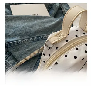 Détail de la fermeture dorée et de la bandoulière chaîne sur un mini sac à pois