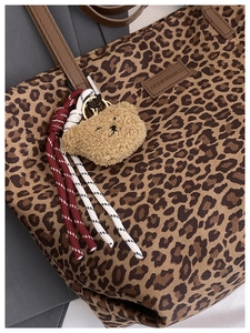 Detailed close-up of leopard print tote bag with plush bear charm and fashion leather tag