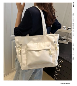 Detail of off-white nylon tote bag showing front flap pocket and decorative rope knot