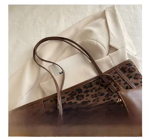 Dettaglio borsa tote leopardata con manici in pelle marrone e mini pochette zip