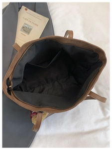 Detail view of large brown tote bag interior with zipper closure and black fabric lining