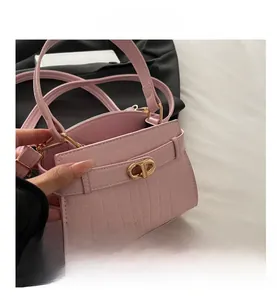 Détail du mini sac à main rose gaufré croco avec fermoir doré et structure latérale à soufflet