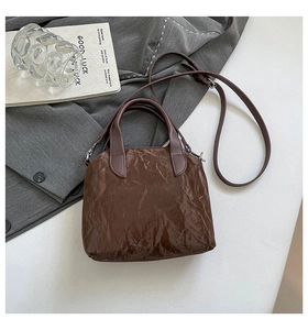 Vue détaillée du sac à main en cuir plissé marron foncé avec poignées et bandoulière
