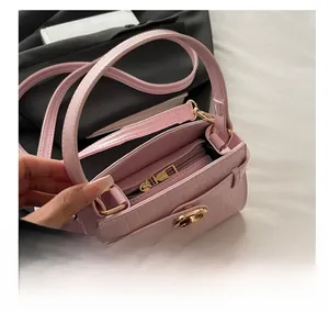 Détail du mini sac rose à motif croco avec fermoir rotatif en métal et zip fluide