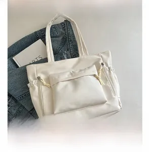 Detail view of a white tote bag with front flap pocket and decorative side zippers