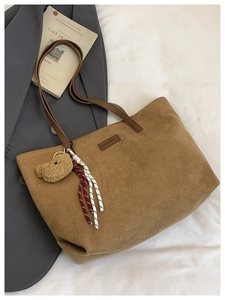 Detailed close-up of brown corduroy tote bag with teddy bear charm and leather strap