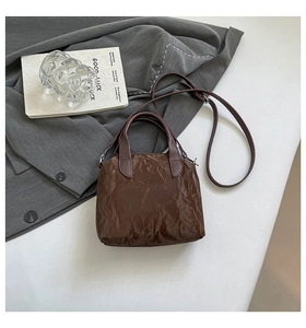 Détail du sac à main marron foncé montrant une texture plissée et des finitions argentées