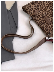 Detail showing leopard print texture, leather strap, and decorative knot on tote bag