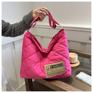 Detail of rose red quilted tote bag with textile label and adjustable strap