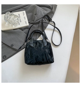 Détails d'un sac à main noir texturé avec doubles poignées et boucles argentées