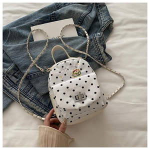 Détail d'un sac à dos blanc à pois avec fermoir métallique et bandoulière chaîne