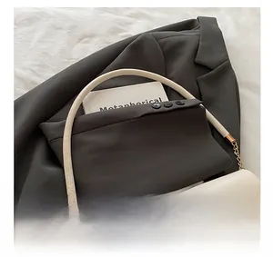 Detail of unique patchwork handbag featuring suit sleeve design and golden chain strap