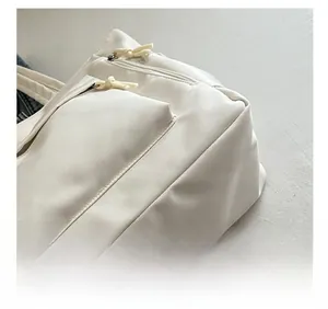 Detail view of precise stitching and zipper pocket on a white canvas tote bag