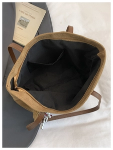 Interior detail of a brown suede tote bag with black fabric lining and gold zipper closure