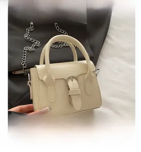 Detail of off-white leather crossbody bag with silver buckle and metal chain strap