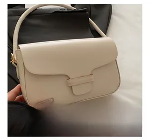 Detail showing cream white crossbody bag with smooth leather texture and gold metal buckle