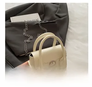 Detail of a creamy white leather handbag with silver buckle on a grey suit jacket
