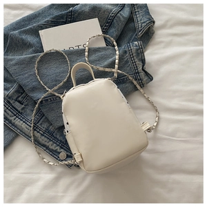 Détail du mini sac à dos beige avec côtés à pois et bandoulière en chaîne métal