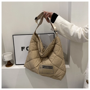 Detail of quilted texture on a large beige tote bag with a fashion logo tag