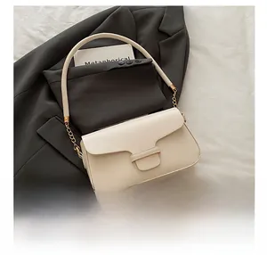 Close-up of cream shoulder bag with golden metal clasp and chain strap detail